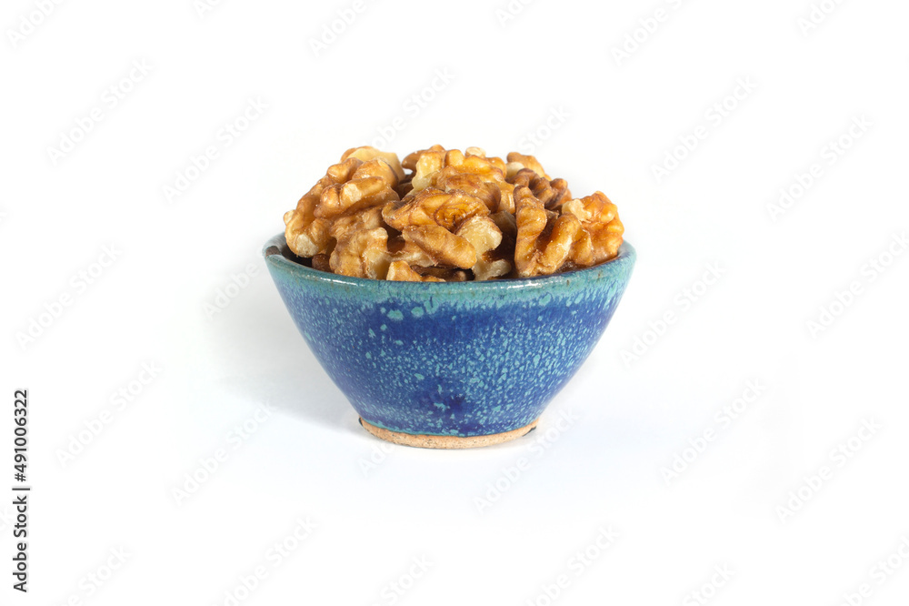 Walnut Halves and Pieces in Small Blue Pottery Bowl Isolated on White