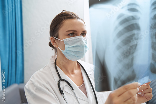 Fotografie Physician in mask looking at chest radiograph