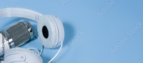 White headphones and microphone for sound recording on a blue background