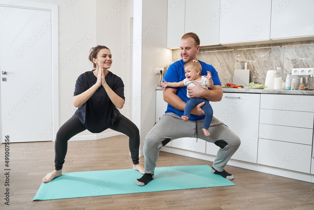 Husband and wife doing squats with their child Husband and wife doing squats with their child
