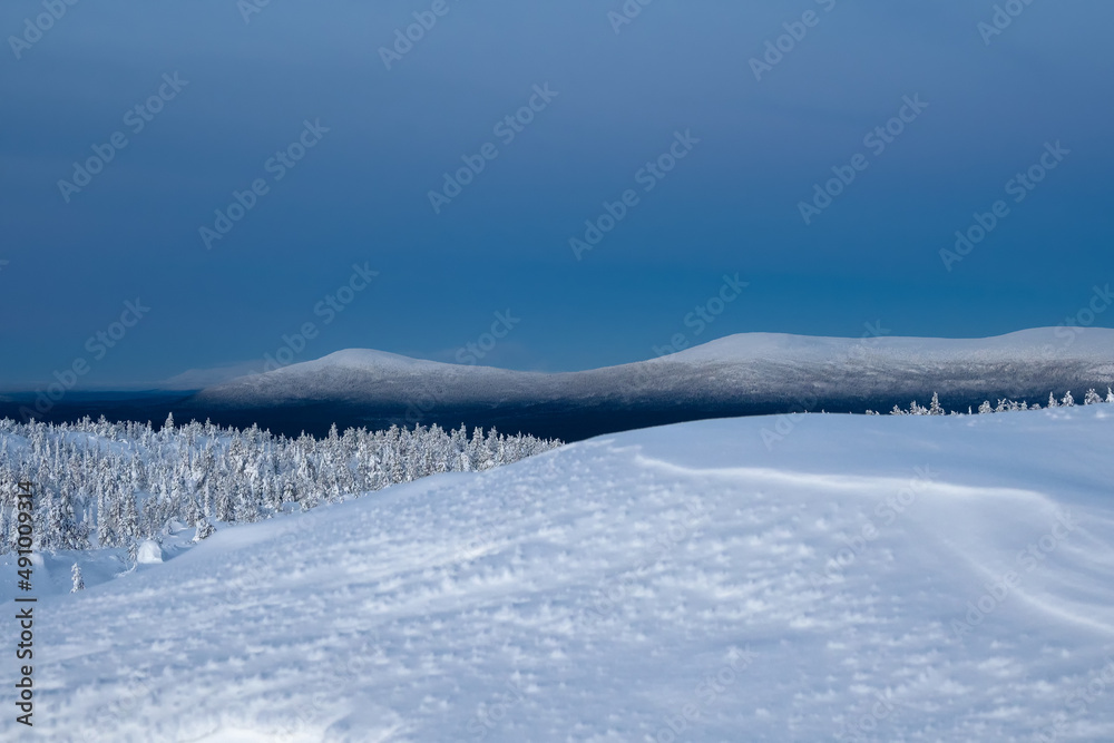 Snow-covered polar cone hills in winter early in the morning. Winter polaris landscape. View of the snow-covered hills. Cold winter weather. Harsh northern climate background.