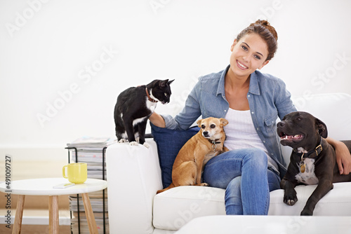 The love rubs off on everybody in her house. Shot of a beautiful young woman relaxing on the couch with her pets. © Mariusz S/peopleimages.com
