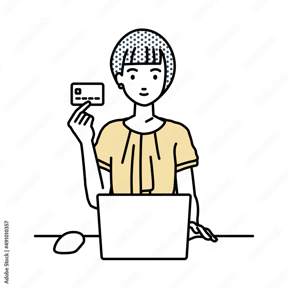 デスクで座ってPCを使いながらクレジットカードを手に持っているオフィスカジュアルの女性