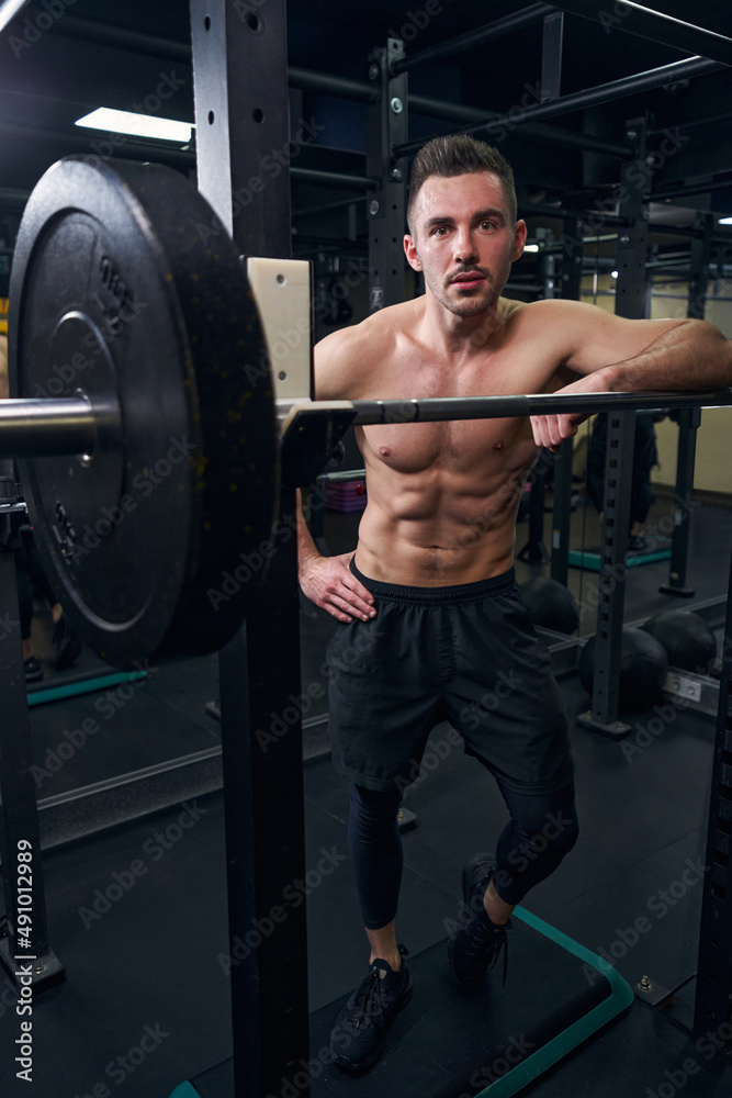 Handsome male person leaning on the barbell