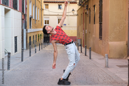 Young caucasian man with long false nails dancing at street, steps of contemporary dance.