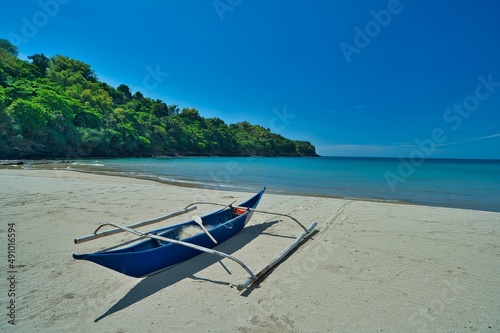 Small boat in sunny blue sky landscape view of beach resort area on white sand in Philippines