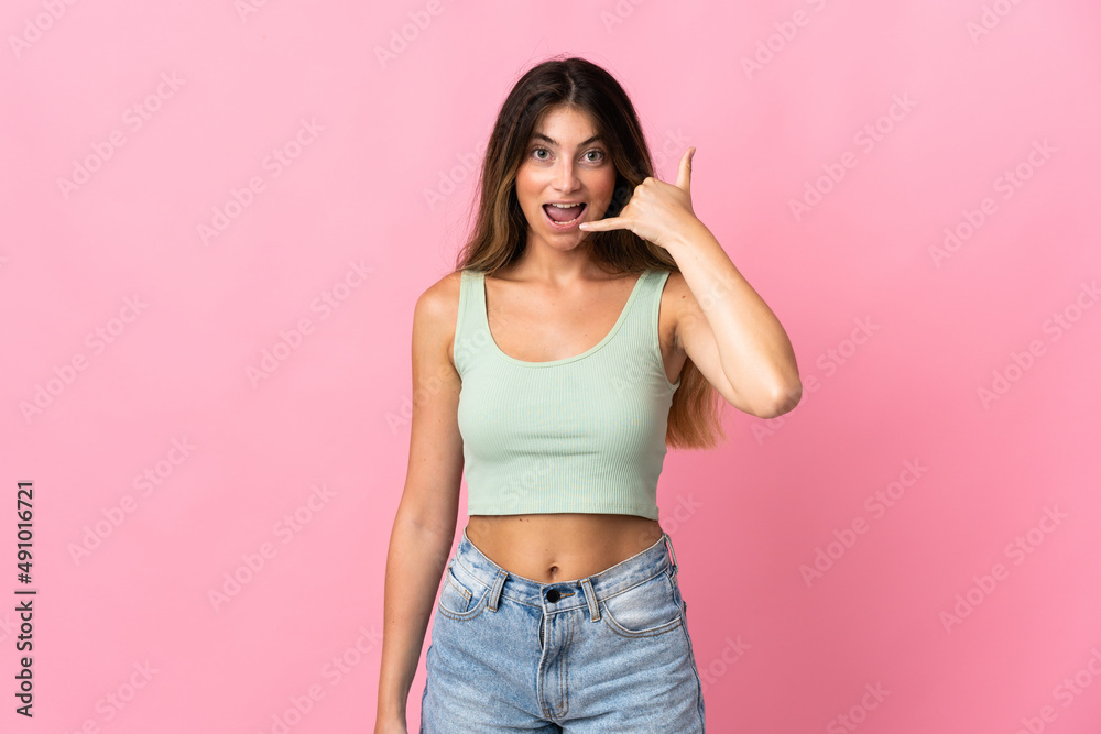Young caucasian woman isolated on pink background making phone gesture. Call me back sign Young caucasian woman isolated on pink background making phone gesture. Call me back sign
