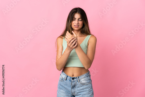 Young caucasian woman isolated on pink background suffering from pain in hands