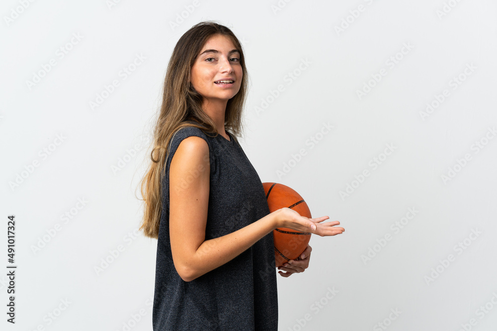 Young woman playing basketball isolated on white background extending hands to the side for inviting to come Young woman playing basketball isolated on white background extending hands to the side for inviting to come