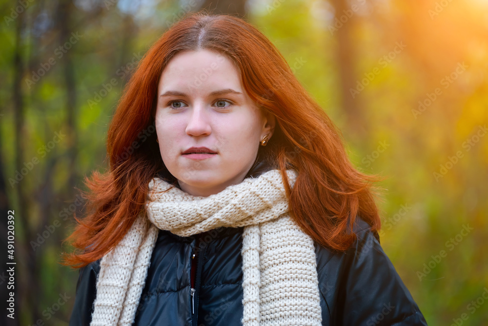 portrait of a red-haired smiling girl in a jacket and scarf against the background of autumn nature and bright sun concept of human emotion portrait of a red-haired smiling girl in a jacket and scarf against the background of autumn nature and bright sun concept of human emotion