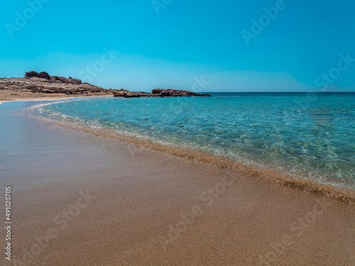 smooth waves of a turquoise sea gently touch the sandy Diakofti beach  Karpathos island  Greece.