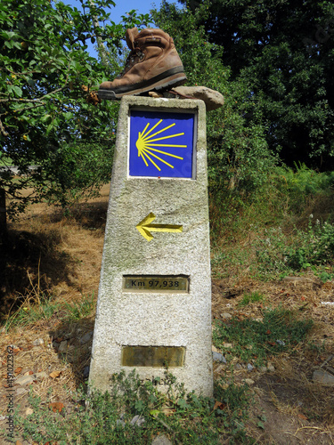 Calzado roto de un peregrino durante el camino de Santiago, colocado sobre un punto kilométrico