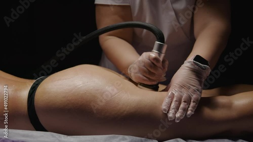 Sexy buttocks woman receiving anti-ageing anti-cellulite massage vacuum rf lifting in spa salon. Wellness body and skin care, beauty treatment, receiving rejuvenation procedure. Black dark background