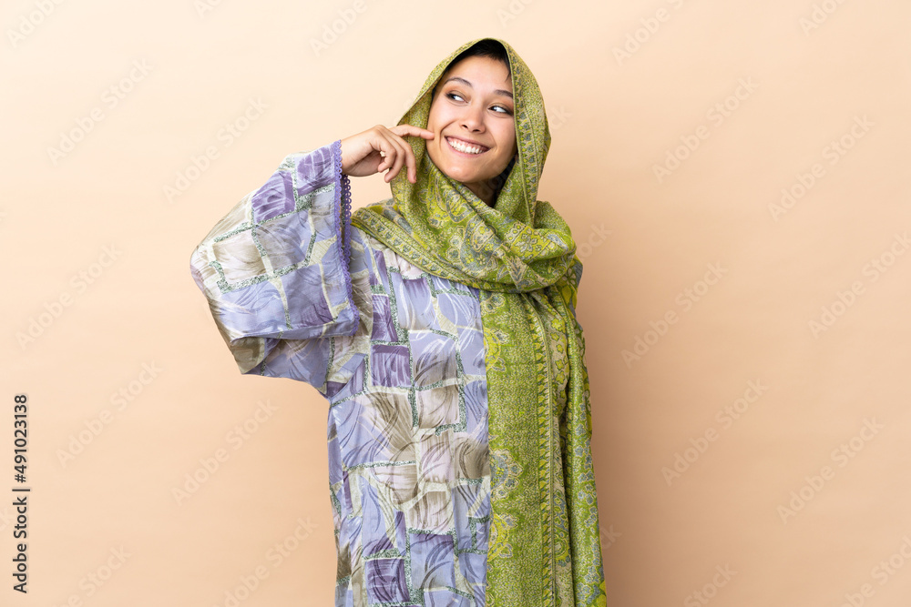 Indian woman isolated on beige background laughing Indian woman isolated on beige background laughing