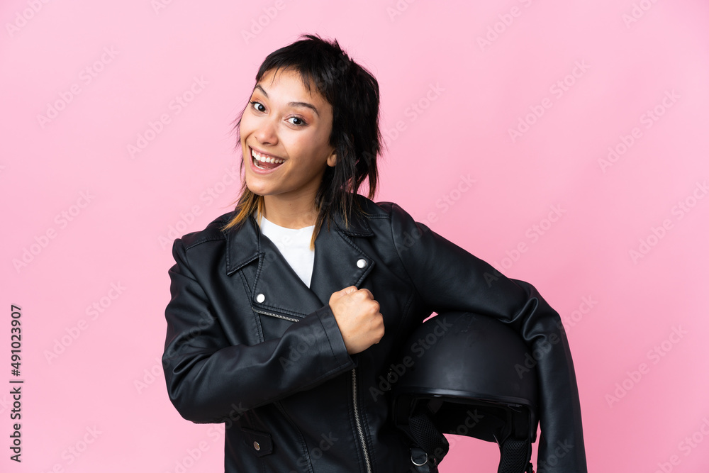 Young Uruguayan woman holding a motorcycle helmet over isolated pink background celebrating a victory Young Uruguayan woman holding a motorcycle helmet over isolated pink background celebrating a victory