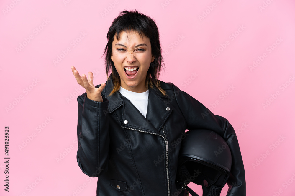 Young Uruguayan woman holding a motorcycle helmet over isolated pink background unhappy and frustrated with something Young Uruguayan woman holding a motorcycle helmet over isolated pink background unhappy and frustrated with something
