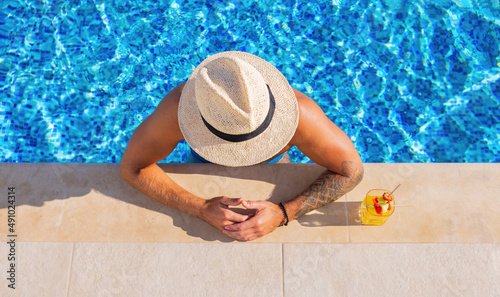 Man drinking cocktail by the pool, view from above