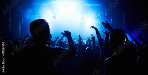 Fototapeta Naklejka Na Ścianę i Meble -  A crowd of people watching a band play on stage at a nightclub. This concert was created for the sole purpose of this photo shoot, featuring 300 models and 3 live bands. All people in this shoot are