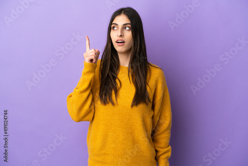 Young caucasian woman isolated on purple background thinking an idea pointing the finger up © luismolinero