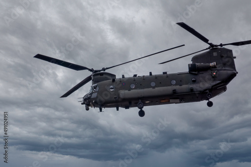 close up of an RAF Chinook tandem-rotor CH-47 helicopter flying fast and low in a cloudy blue grey sky on a military battle exercise, Wilts UK