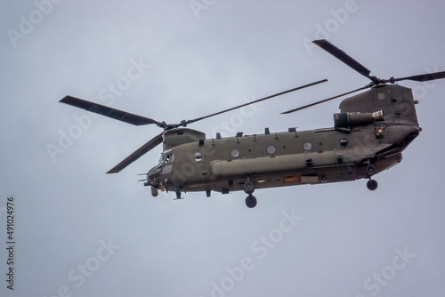 close up of an RAF Chinook tandem-rotor CH-47 helicopter flying fast and low in a cloudy blue grey sky on a military battle exercise, Wilts UK © Martin