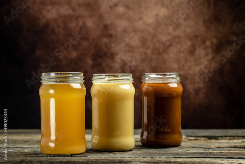 Collection of jars of different types of honey, light, dark and cream, Composition with three jars of honey, closeup