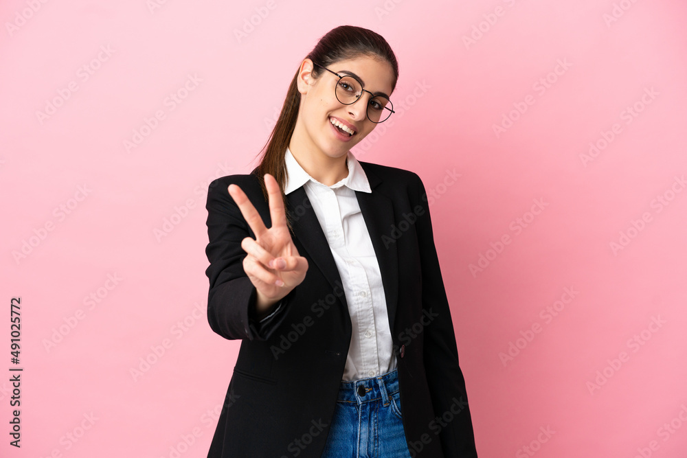 Young caucasian business woman isolated on pink background smiling and showing victory sign Young caucasian business woman isolated on pink background smiling and showing victory sign
