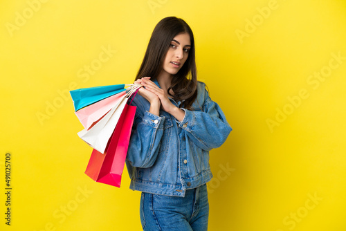 Young caucasian woman isolated on blue background holding shopping bags