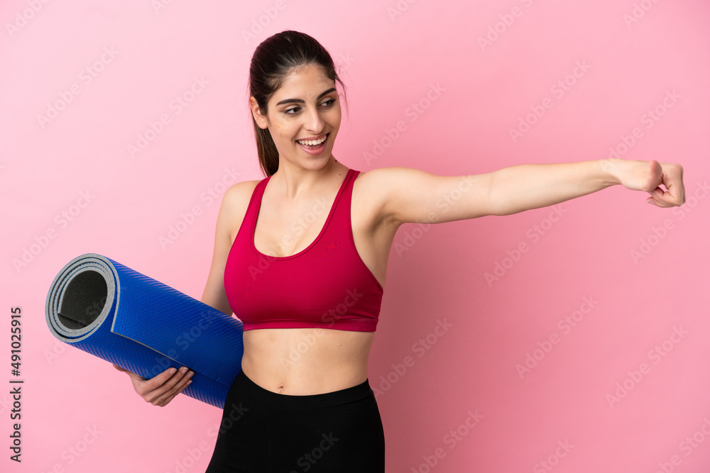 Young sport caucasian woman going to yoga classes while holding a mat giving a thumbs up gesture Young sport caucasian woman going to yoga classes while holding a mat giving a thumbs up gesture