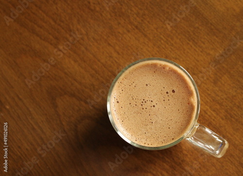 Cup of milk coffee on wooden table, top view, hot drink
