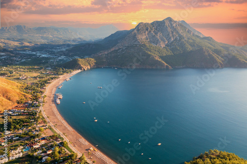 Long beach coast, dark teal sea and bay in Adrasan village Mediterranean coast, great place for holiday. background mountains, forest and sunrise sky. Aerial view with drone. Antalya, TURKEY