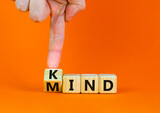 Have a kind mind. Businessman turnsa wooden cube and changes the word Kind to Mind on a beautiful orange table orange background. Business and kind mind concept. Copy space.