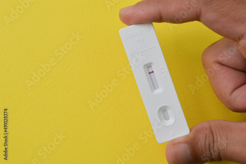 Hand holding Covid-19 Antigen Rapid Test isolated on a yellow background