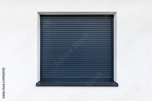 Large window in anthracite color with fully covered external blinds, view from the outside of the building.