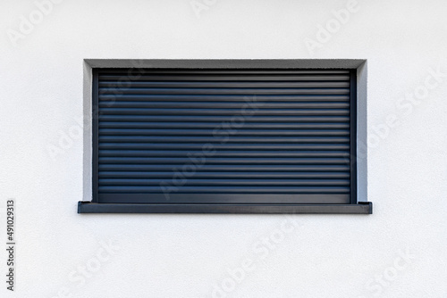 Large window in anthracite color with fully covered external blinds, view from the outside of the building.