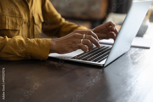 African female employee working at laptop, typing on keyboard. Woman hands close up. Businesswoman in casual, professional working at table, using online app, chatting, writing article. Cropped shot photo