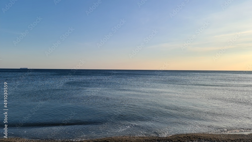 Savona, Italy - February 12, 2022: Panorama of the sea sunset, light above the water, ocean sunrise. Some little waves in winter days.