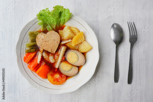 "selat solo is traditional salad food from indonesia. made from hard-boiled eggs, boiled chickpeas, boiled carrots, hash browns and lettuce, steak or bistik.
served on table"
