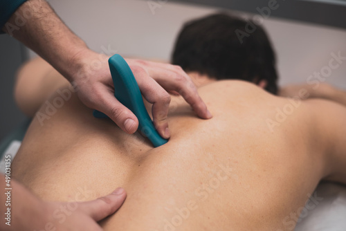 Fotografi A physical therapist uses a trigger point tool on a patient with back pain