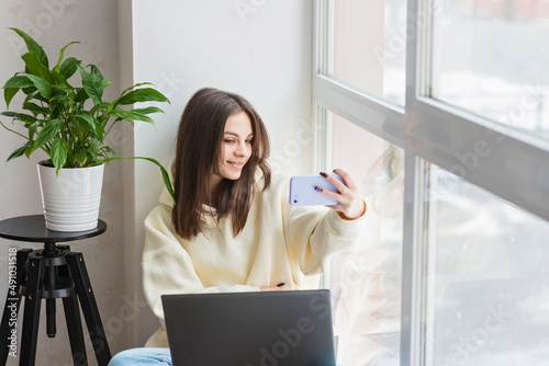 Happy female blogger taking selfie portrait on smartphone camera for social media posting, cheerful teenage girl talking on video call with family or friends via mobile phone.Soft selective focus.