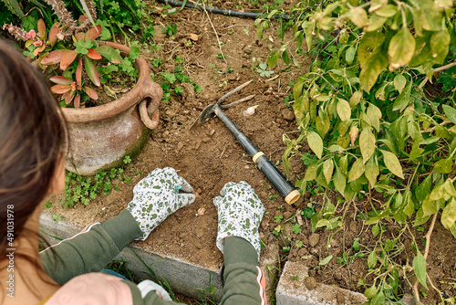 Hands of gardener wearing garden gloves planting flower bulbs in the soil in flower garden. Autumn or spring home gardening.