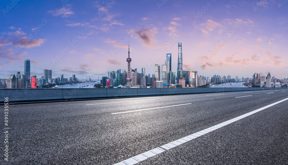 Asphalt highway and city skyline with modern commercial buildings in Shanghai at sunset, China.