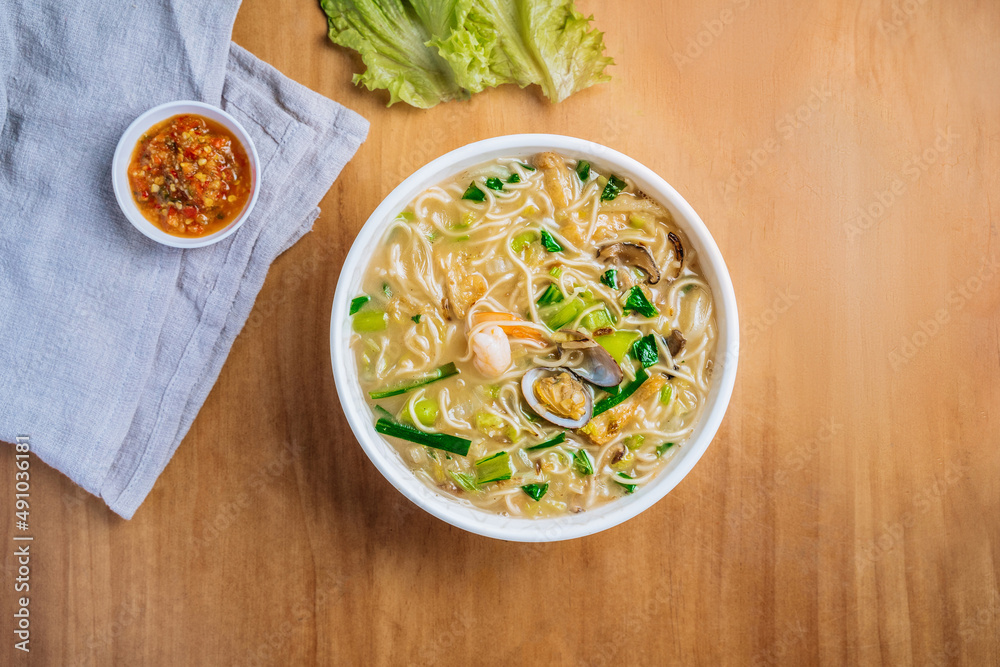 singaporean food Xinghua Lor Mee in a dish with chili sauce, and king's salad leaf top view on wooden background singaporean food Xinghua Lor Mee in a dish with chili sauce, and king's salad leaf top view on wooden background