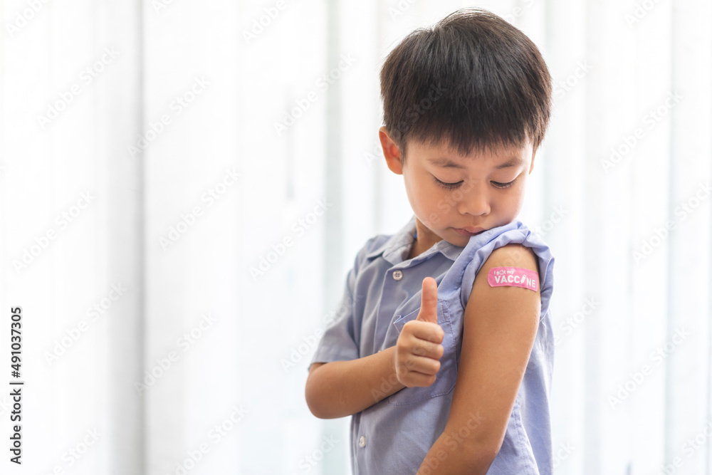 Portrait of happy smile vaccinated little asian kid boy children ages 5 to 11 years old posing show arm with medical plaster after Injection vaccine Covid-19 protection.coronavirus vaccination kid Portrait of happy smile vaccinated little asian kid boy children ages 5 to 11 years old posing show arm with medical plaster after Injection vaccine Covid-19 protection.coronavirus vaccination kid