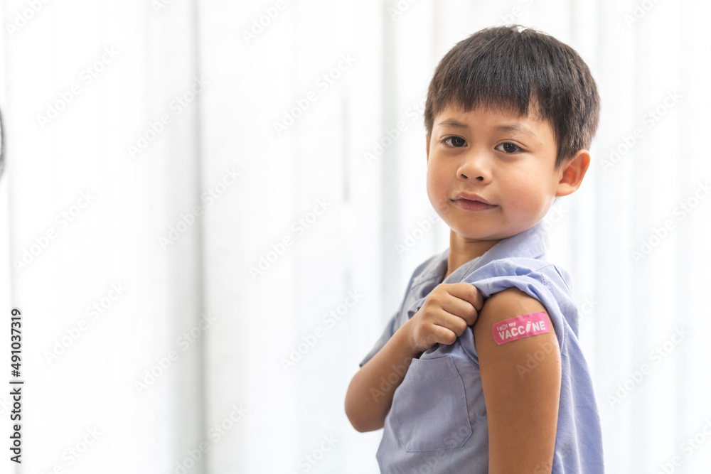 Portrait of happy smile vaccinated little asian kid boy children ages 5 to 11 years old posing show arm with medical plaster after Injection vaccine Covid-19 protection.coronavirus vaccination kid Portrait of happy smile vaccinated little asian kid boy children ages 5 to 11 years old posing show arm with medical plaster after Injection vaccine Covid-19 protection.coronavirus vaccination kid