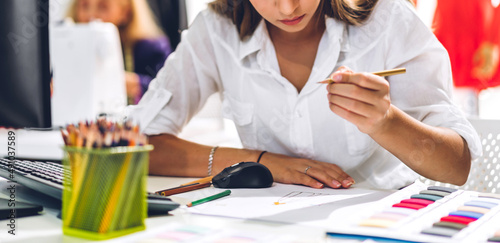 Portrait of young beautiful pretty owner business woman fashion designer stylish sitting and working.Attractive young designer girl use desktop conputer and colorful fabrics at fashion workshop studio photo