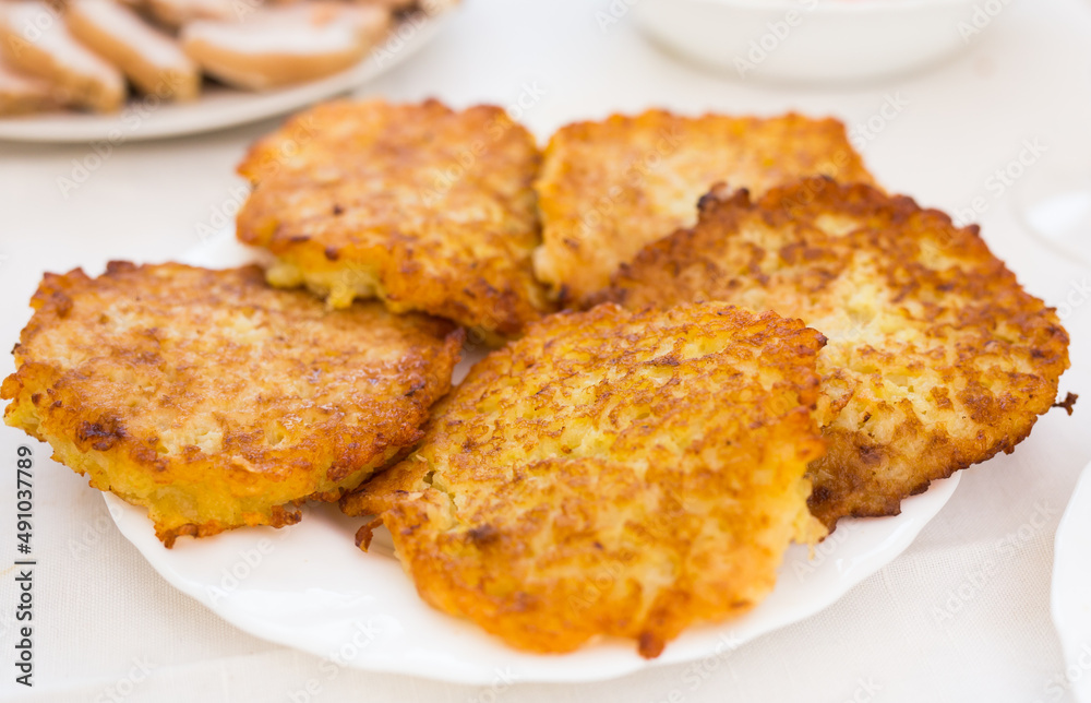 Potato pancakes with sour cream on white plate Potato pancakes with sour cream on white plate