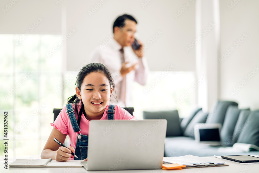 School kid little student girl learning and looking at laptop computer making homework studying knowledge with online education e-learning system.children video conference with teacher tutor at home