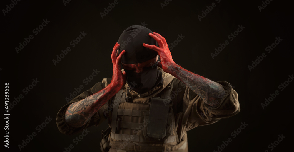 photo of a man in a military uniform and balaclava with a bloody face and hands up to the elbow in blood on a black background photo of a man in a military uniform and balaclava with a bloody face and hands up to the elbow in blood on a black background