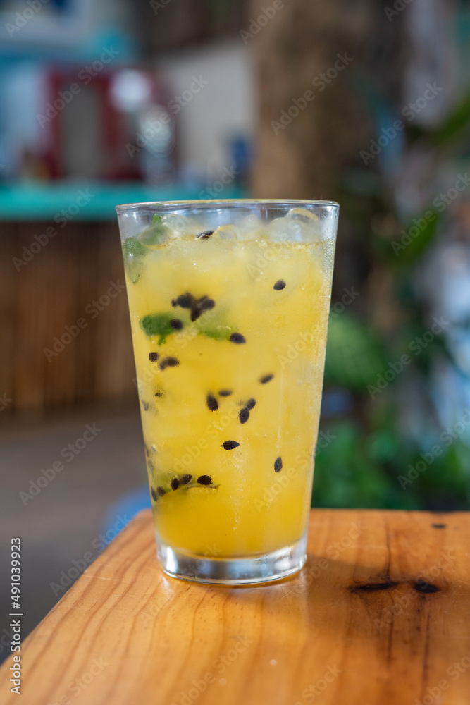 A glass of passion fruit mojito with mint and ice on a table A glass of passion fruit mojito with mint and ice on a table